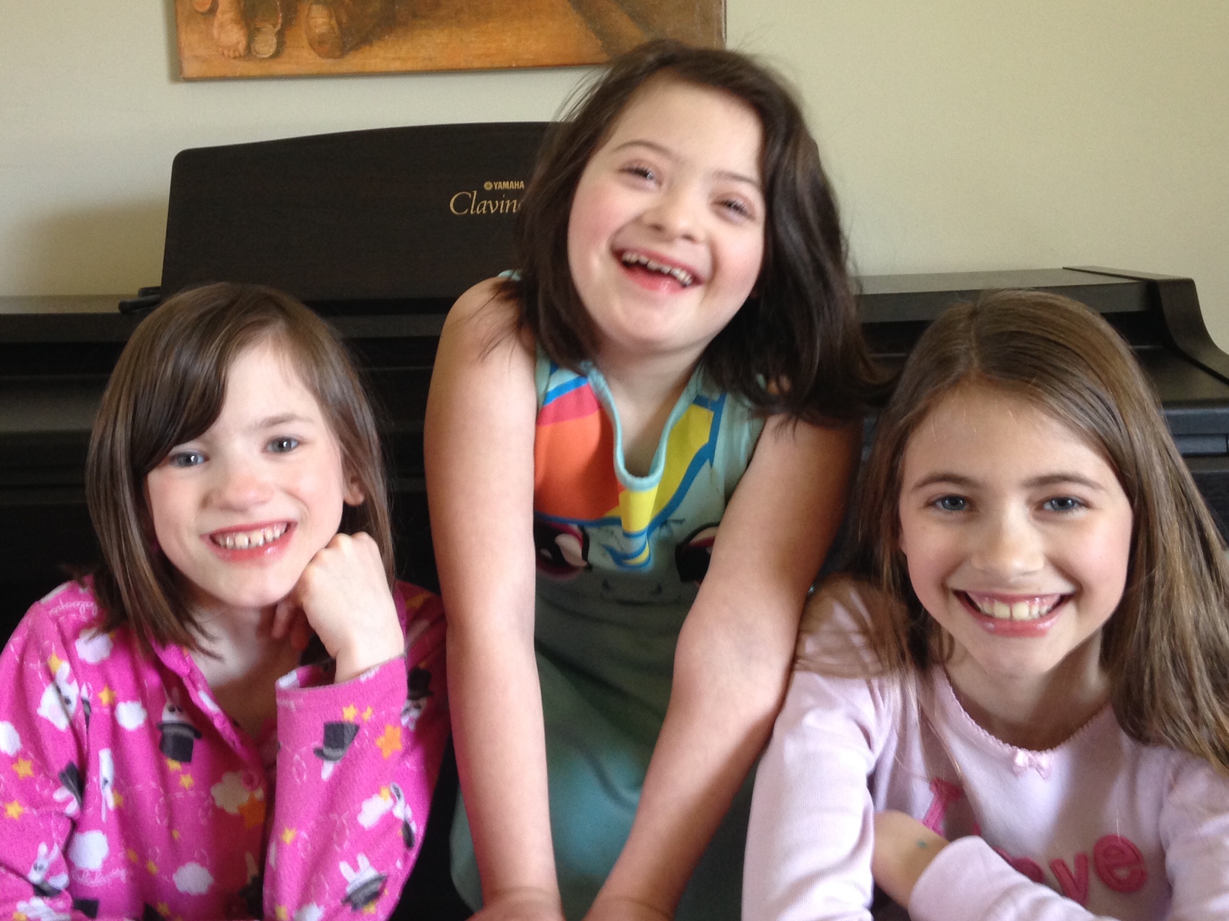 Three sisters smiling at the camera, two have disabilities, one does not