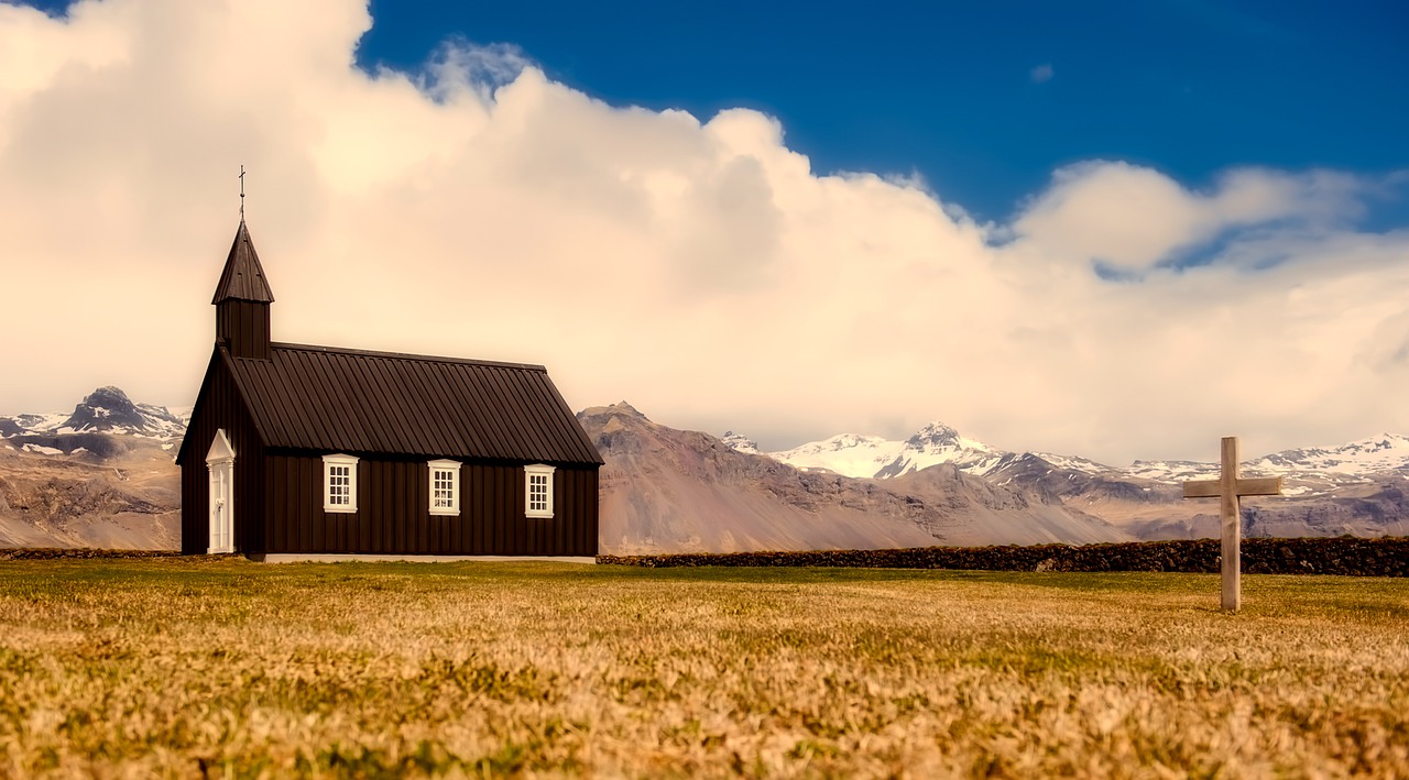 Small brown church against mountains in field